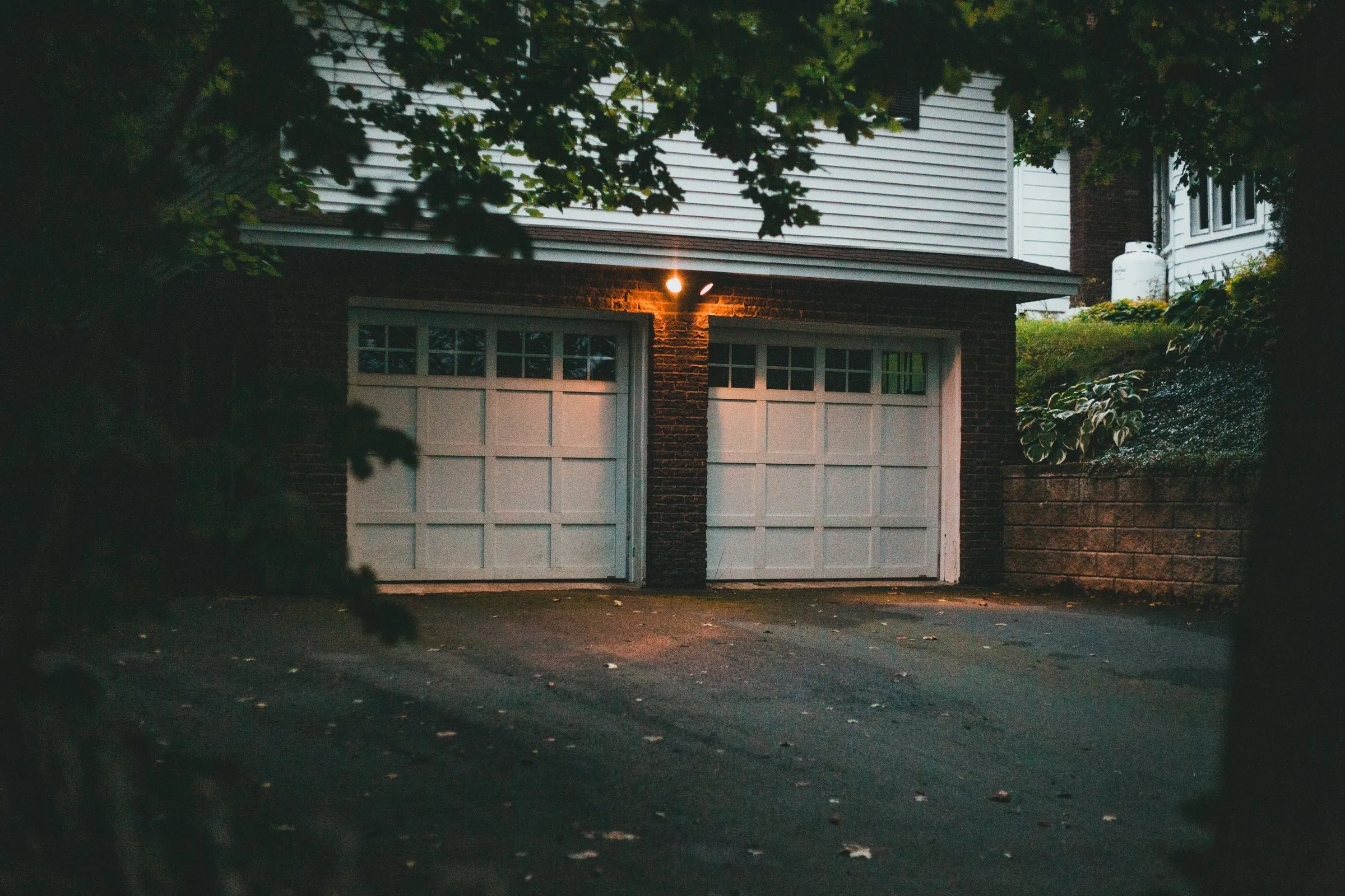 A two-car garage at dusk with the porch light on and both doors closed