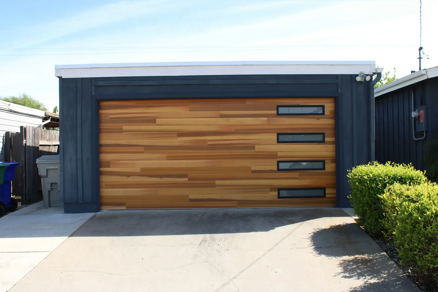 A modern cedar-look garage door with a column of windows