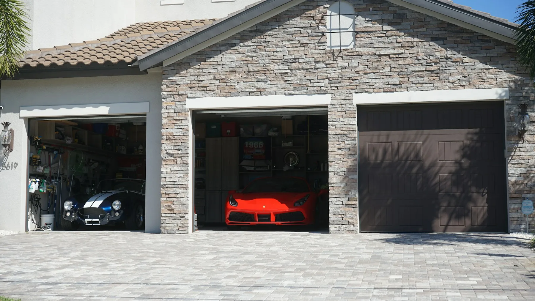 A three-car garage in a stone-faced house, two doors open
